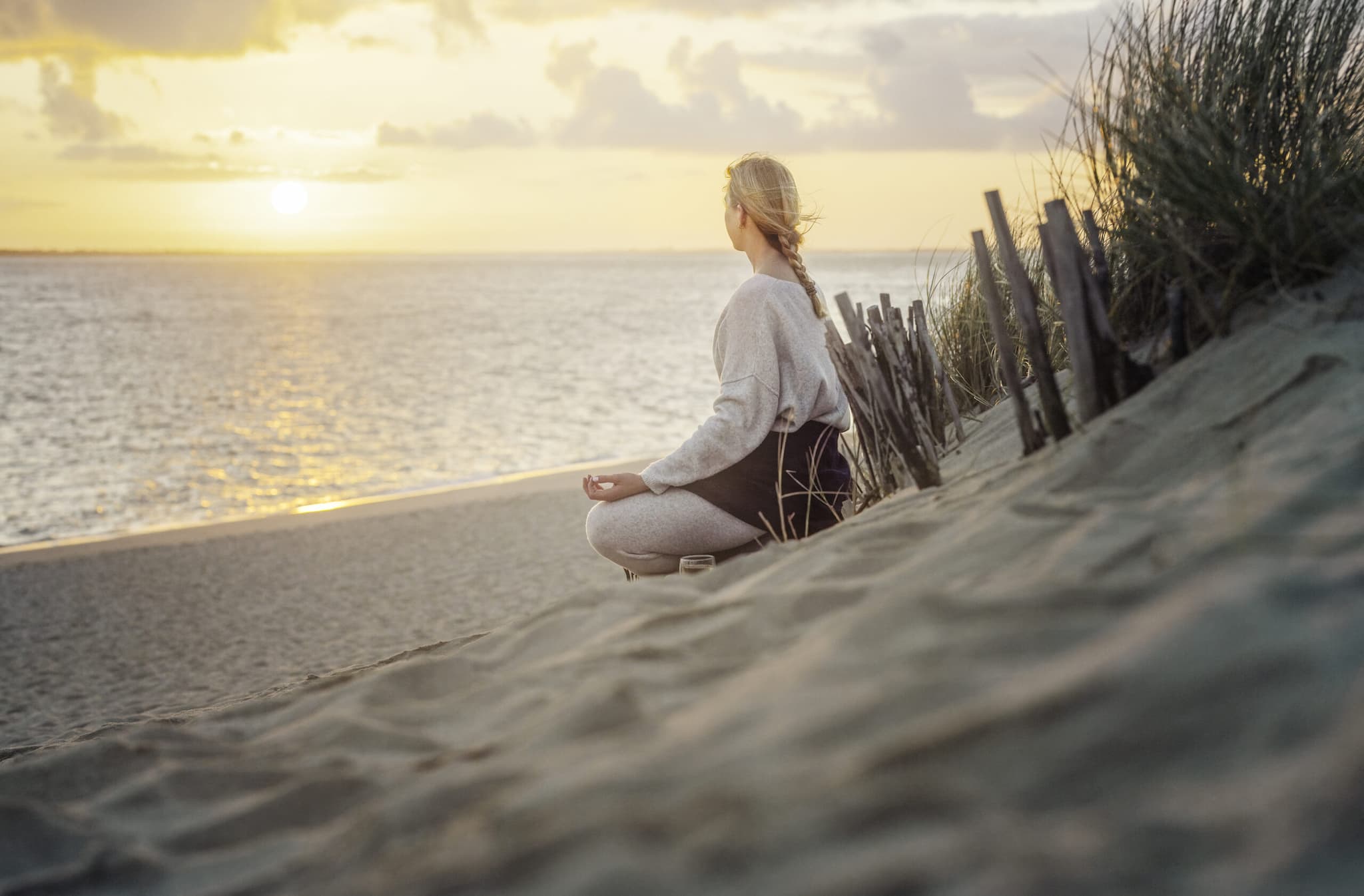 Frau sitz am Strand von Sylt und meditiert